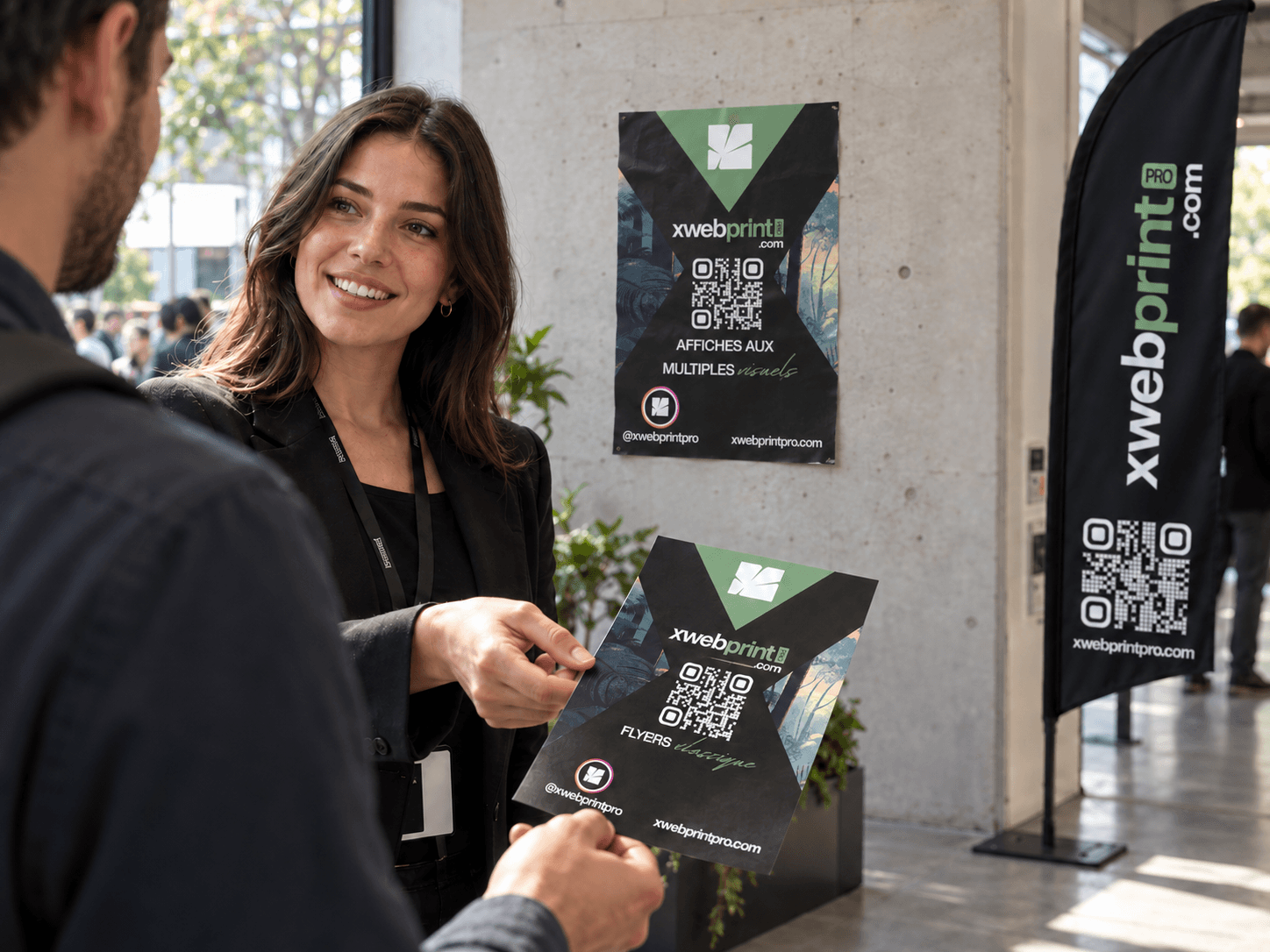 Une personne remet un flyer XWEB ; une affiche est collée au mur et une flamme publicitaire est installée à côté.